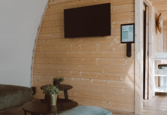 Salon moderne avec murs en bois, télévision, climatisation et plantes au Big Oak Tent, Sallandshoeve.