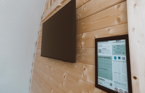 Innenwand im Big Oak Tent im Ferienpark Sallandshoeve, Niederlande, mit Fernseher und Infotafel.