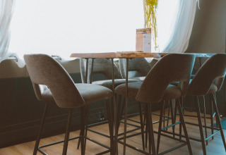 Moderne barkrukken en tafel in Big Oak Tent, Holiday Park Sallandshoeve, Nederland, voor een zonnig raam.