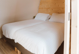 Zwei Einzelbetten mit weißen Laken im Big Oak Tent im Holiday Park Sallandshoeve, Niederlande, Holzwand.