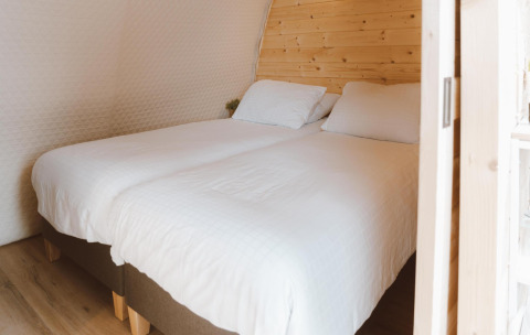 Zwei Einzelbetten mit weißen Laken im Big Oak Tent im Holiday Park Sallandshoeve, Niederlande, Holzwand.