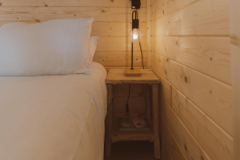 Acogedor rincón de dormitorio en Big Oak Tent en Holiday Park Sallandshoeve con cama, lámpara y mesa.