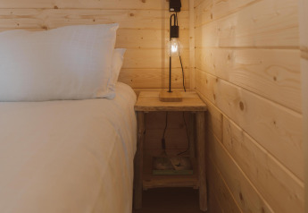 Hyggeligt soveværelse i Big Oak Tent med træpaneler, seng, natbord og lampe i Holiday Park Sallandshoeve.