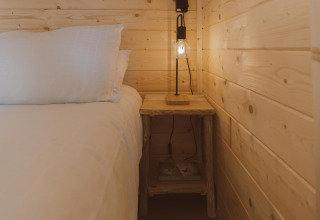 Gemütliches Schlafzimmer in der Big Oak Tent mit Holzwänden, Bett, Nachttisch und Lampe in Sallandshoeve.