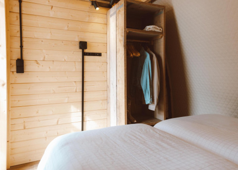 Intérieur du Big Oak Tent au Holiday Park Sallandshoeve, Pays-Bas, avec lits et armoire en bois.