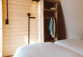 Intérieur du Big Oak Tent au Holiday Park Sallandshoeve, Pays-Bas, avec lits et armoire en bois.