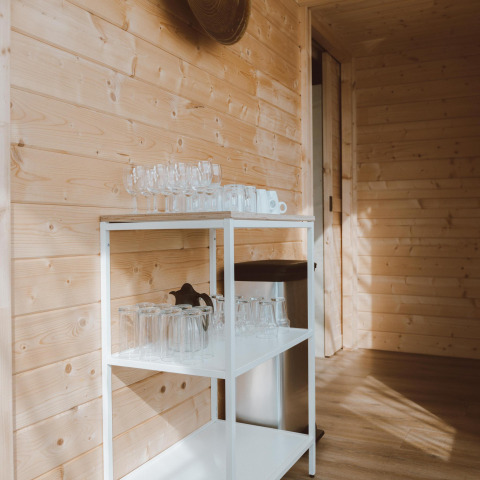 Regal mit Gläsern neben Holzwand im Big Oak Tent, Holiday Park Sallandshoeve, Niederlande.