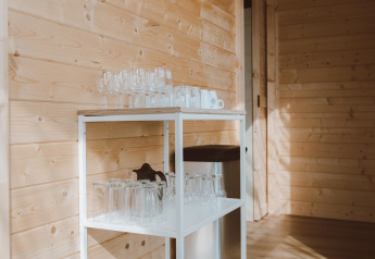 Glazen op een rek bij houten wand in Big Oak Tent, Holiday Park Sallandshoeve, Nederland, daglicht.