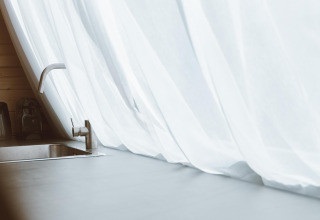 Moderne Spüle mit Wasserhahn und weißen Vorhängen im Big Oak Tent, Holiday Park Sallandshoeve, Niederlande.