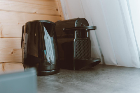 Sort elkedel og kaffemaskine på en køkkenbordplade ved siden af et vindue i Big Oak Tent, Holiday Park Sallandshoeve.