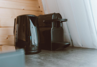 Sort elkedel og kaffemaskine på en køkkenbordplade ved siden af et vindue i Big Oak Tent, Holiday Park Sallandshoeve.