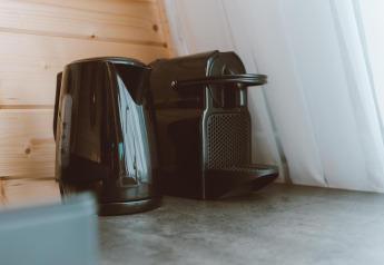 Sort elkedel og kaffemaskine på en køkkenbordplade ved siden af et vindue i Big Oak Tent, Holiday Park Sallandshoeve.