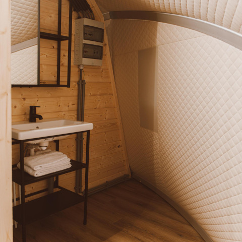 Lavabo moderno con espejo, paneles de madera y paredes acolchadas en Big Oak Tent, Holiday Park Sallandshoeve, Países Bajos.