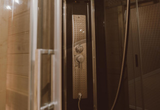 Modern shower cabin with glass door and panel in Big Oak Tent at Holiday Park Sallandshoeve, Netherlands.