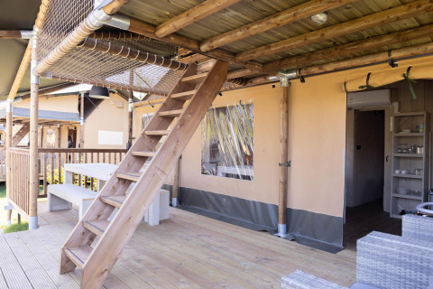Houten terras met trap naar een net, picknickbank en safaritent bij Ranger Lodge in Sallandshoeve.