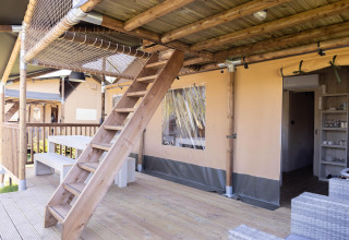 Houten terras met trap naar een net, picknickbank en safaritent bij Ranger Lodge in Sallandshoeve.
