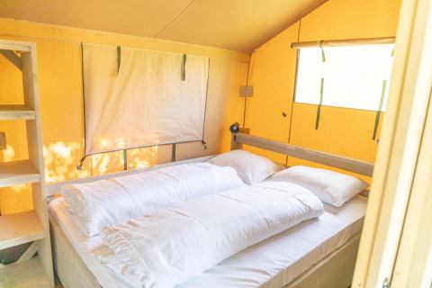 Vista interna di una tenda safari Ranger Lodge con letto matrimoniale e finestre all’Holiday Park Sallandshoeve.