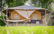 Tienda tipo safari cottage con terraza, hamaca y sofá en Holiday Park Sallandshoeve, Países Bajos.
