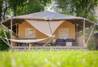 Tienda tipo safari cottage con terraza, hamaca y sofá en Holiday Park Sallandshoeve, Países Bajos.