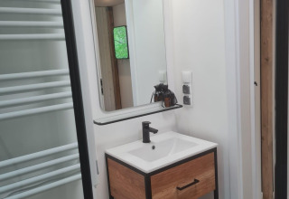 Baño moderno en Tiny house l en Camping Si-Es-An, Países Bajos, con espejo y mueble de madera.