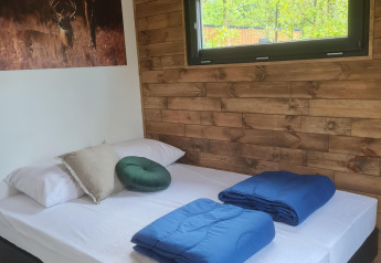 Accogliente camera da letto nel Tiny House I al Camping Si-Es-An nei Paesi Bassi, con muro in legno.