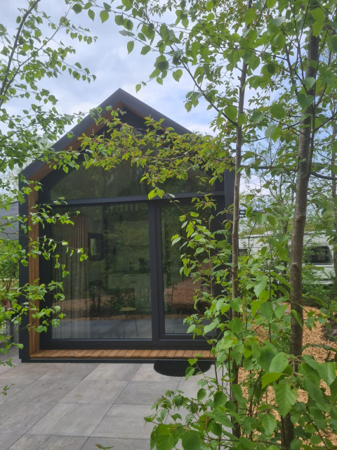 Casa diminuta llamada Tiny house l en Camping Si-Es-An en Países Bajos, rodeada de árboles verdes.