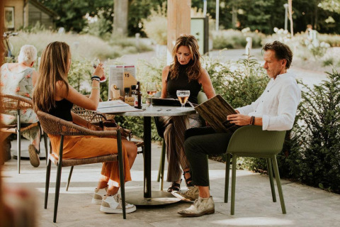 Tres personas sentadas al aire libre en una mesa en Tiny house l de Camping Si-Es-An en los Países Bajos.