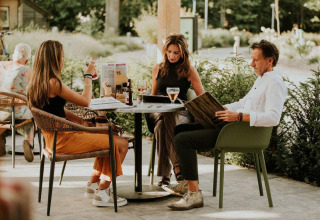 Tres personas sentadas al aire libre en una mesa en Tiny house l de Camping Si-Es-An en los Países Bajos.