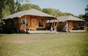 Safari-telte på Camping Si-Es-An i Holland med familier der leger foran rummelige luksustelte i naturen.