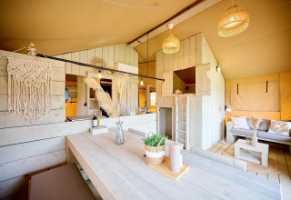 Interior de tienda Safari en Camping Si-Es-An en Países Bajos, con decoración de madera y zona de estar acogedora.