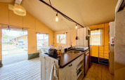 Binnenkant van de safaritentlodge op Camping Si-Es-An, Nederland, met keuken en eetruimte.