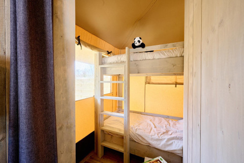 Interior de una tienda Safari en Camping Si-Es-An, Países Bajos, con literas de madera y peluche de panda.