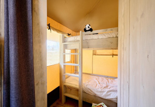 Intérieur d'une tente Safari au Camping Si-Es-An aux Pays-Bas, avec lits superposés en bois et panda en peluche.