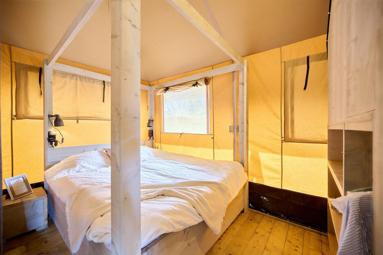 Vista interior de una tienda safari con cama doble en Camping Si-Es-An, Países Bajos.