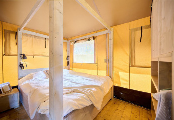 Vue intérieure d'une tente safari avec un lit double au Camping Si-Es-An aux Pays-Bas.