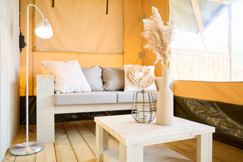 Área de estar luminosa y acogedora en una tienda safari de Camping Si-Es-An en Países Bajos, decoración moderna.