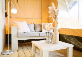 Área de estar luminosa y acogedora en una tienda safari de Camping Si-Es-An en Países Bajos, decoración moderna.