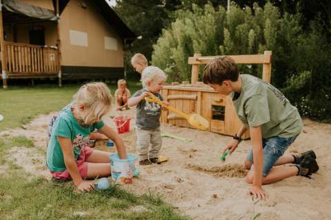 Des enfants jouent dans un bac à sable près d’une tente safari au Camping Si-Es-An aux Pays-Bas.