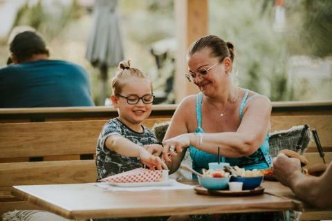 Madre e hijo disfrutan de una comida juntos en una tienda safari de Camping Si-Es-An, Países Bajos, sonriendo.