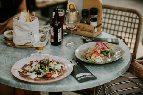 Repas sous tente Safari au Camping Si-Es-An, Pays-Bas, avec vin, bière, pain et salade fraîche sur la table.