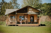 Familia disfrutando afuera de la Ranger Lodge en Camping Si-Es-An en los Países Bajos, rodeados de naturaleza.