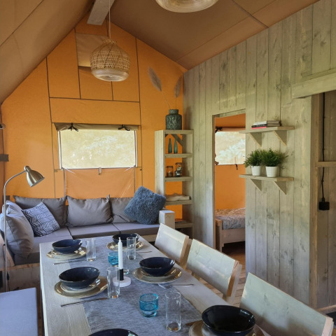 Interior de la Ranger lodge en Camping Si-Es-An, Países Bajos, con mesa de comedor y zona de estar acogedora.