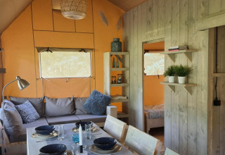 Interior de la Ranger lodge en Camping Si-Es-An, Países Bajos, con mesa de comedor y zona de estar acogedora.