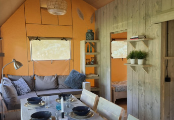 Interno della Ranger lodge al Camping Si-Es-An nei Paesi Bassi con tavolo da pranzo e area salotto accogliente.
