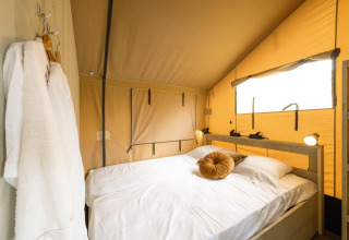 Acogedor dormitorio en la Ranger lodge de Camping Si-Es-An, Países Bajos, con cama doble y luz natural.