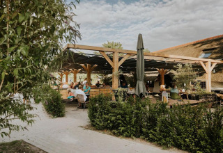 Terraza al aire libre en Ranger lodge en Camping Si-Es-An, Países Bajos, con huéspedes y pérgola de madera