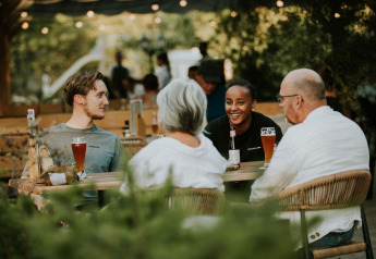 Cuatro personas disfrutan de bebidas y conversación al aire libre en Ranger lodge en Camping Si-Es-An, Países Bajos.