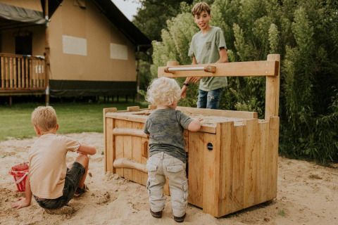 Kinder spielen in einer Sandkiste vor der Ranger-Lodge auf Camping Si-Es-An in den Niederlanden.