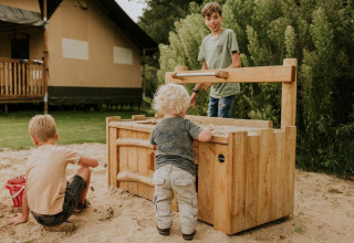 Niños jugando en una caja de arena junto a Ranger lodge en Camping Si-Es-An en los Países Bajos.