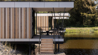 Hébergement de glamping moderne sur l'eau avec véranda, bardage bois et vue sur la nature.